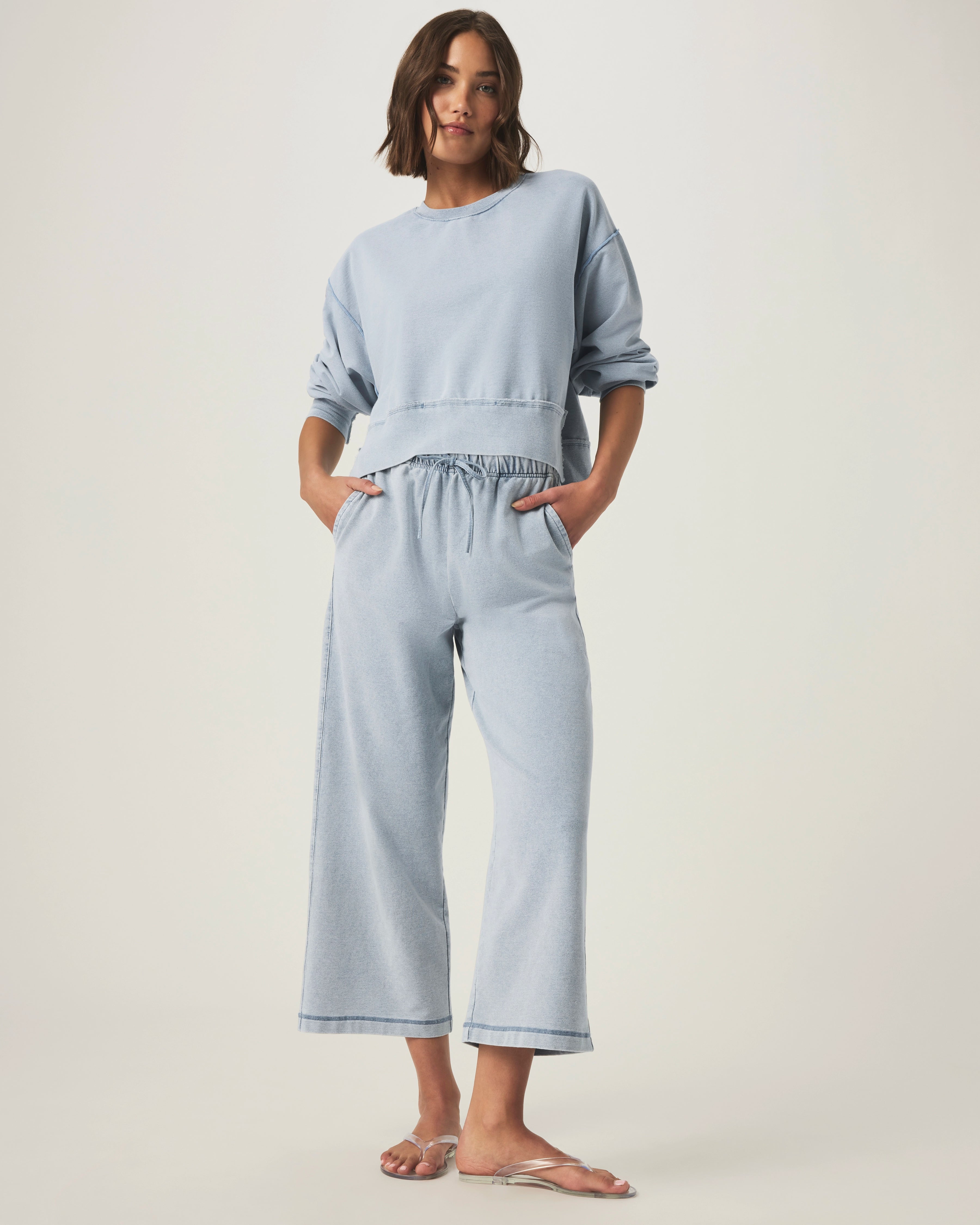 person wearing light blue grey terry pants and matching sweater with drawstring and elastic waistband