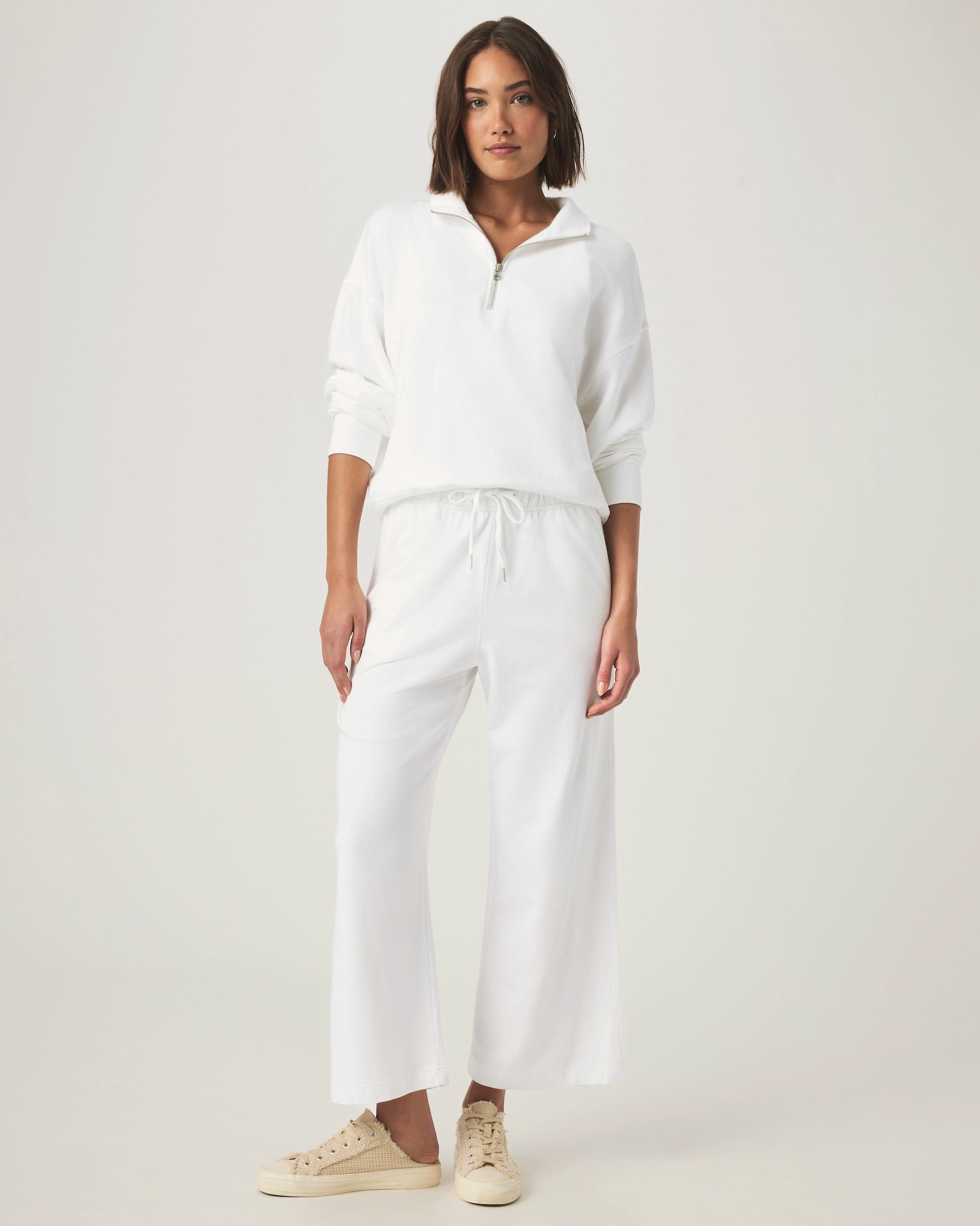 woman wearing white wide-leg terry cloth drawstring pants and matching half zip sweater