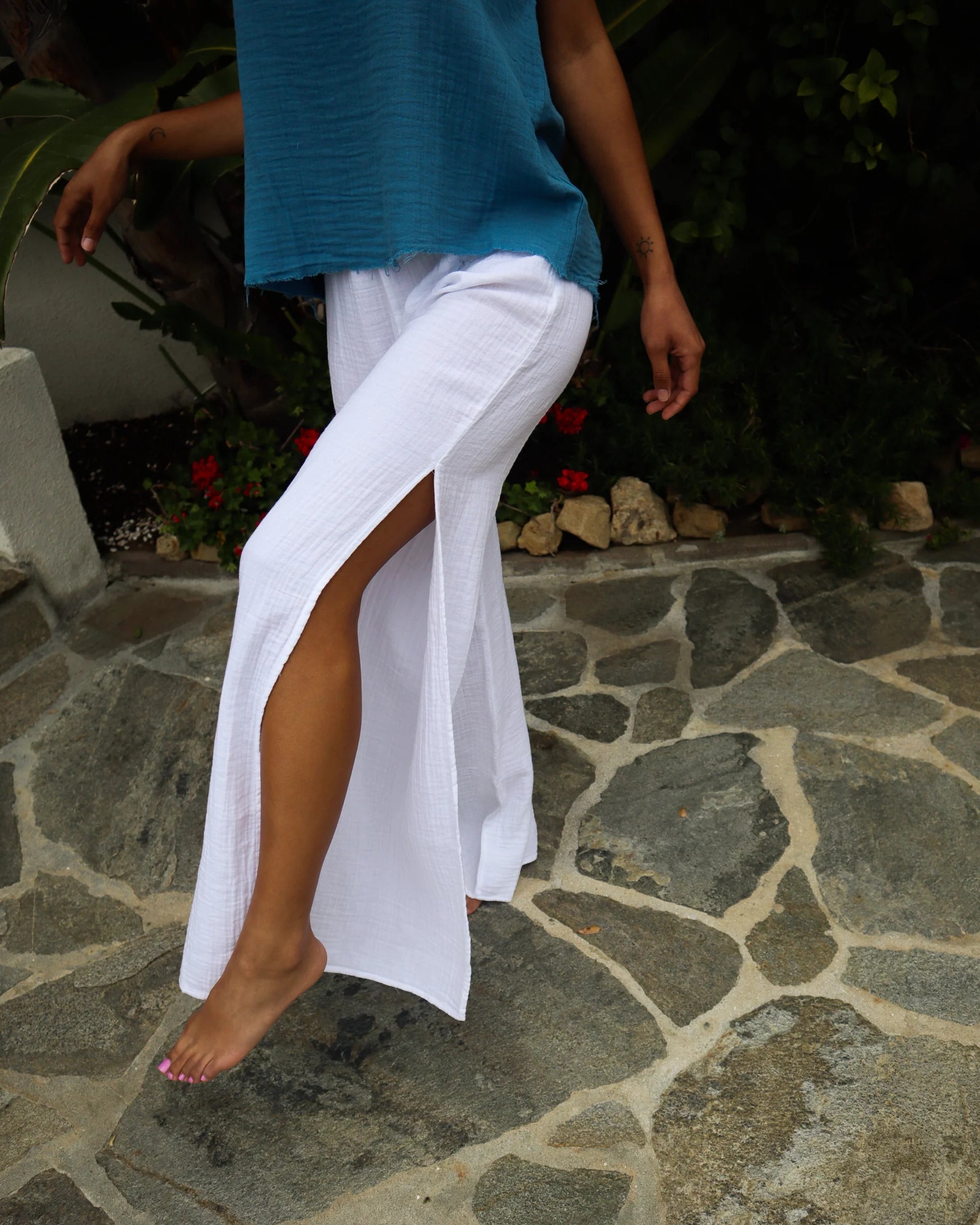 A person wearing white cotton gauze slit pants with high side seam slits