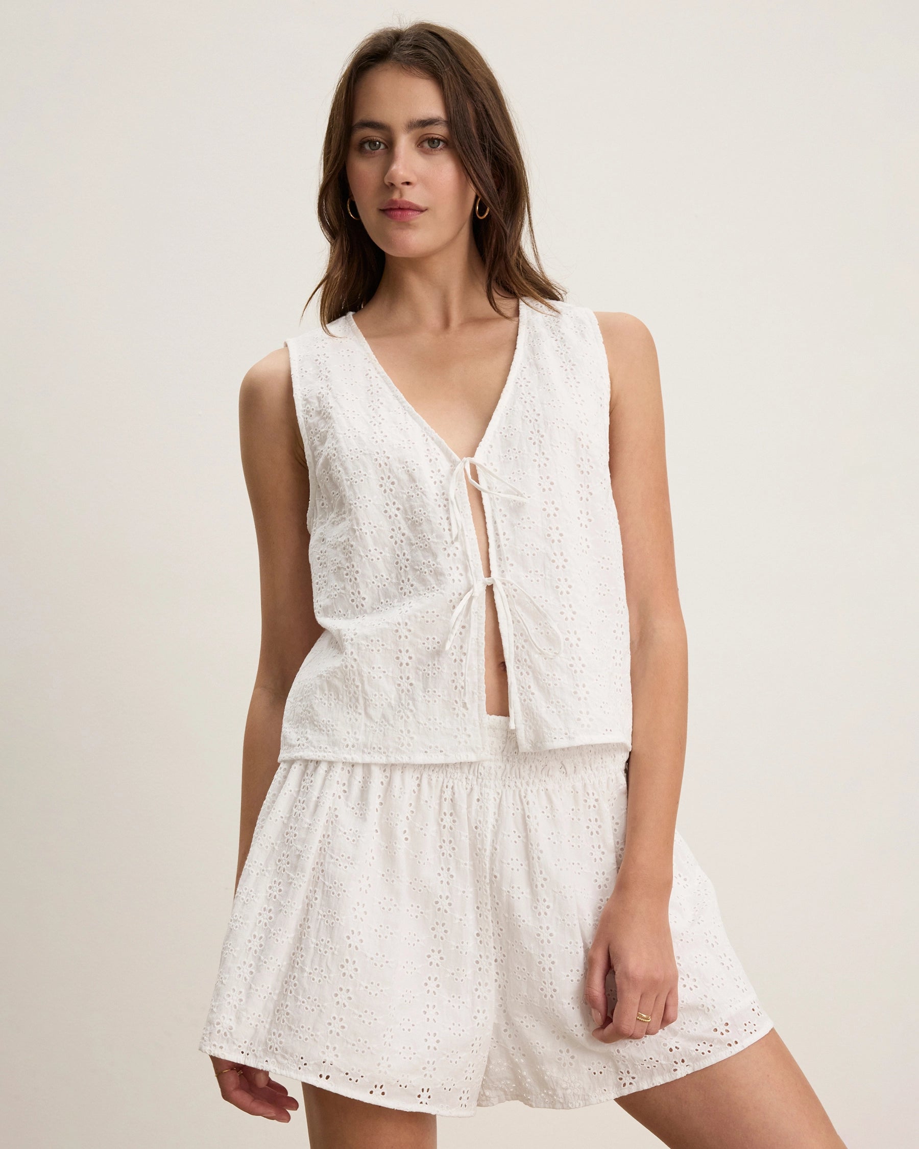 Woman wearing a white lace eyelet blouse with matching shorts