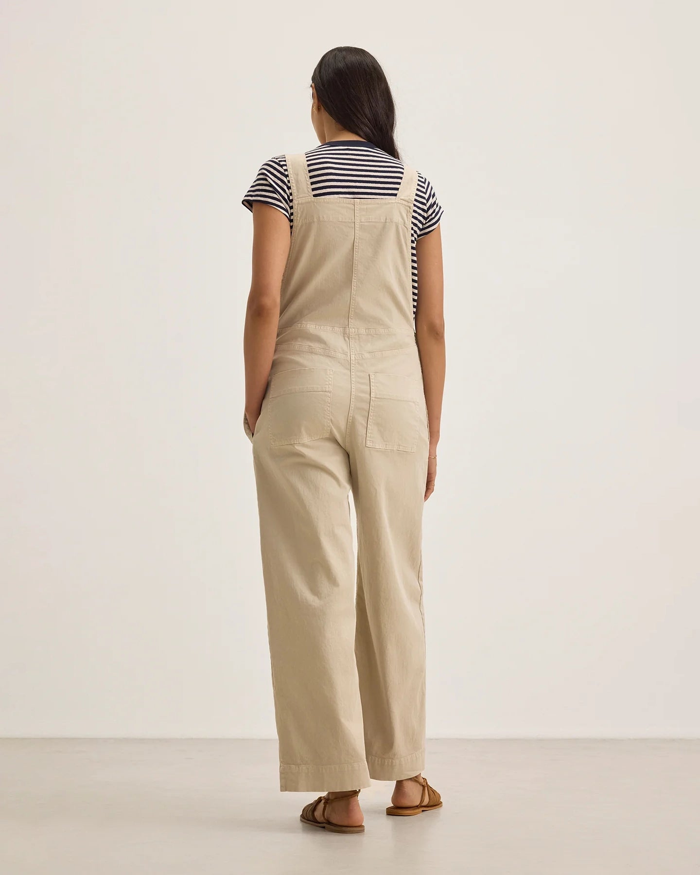 Woman wearing beige overalls with a striped shirt