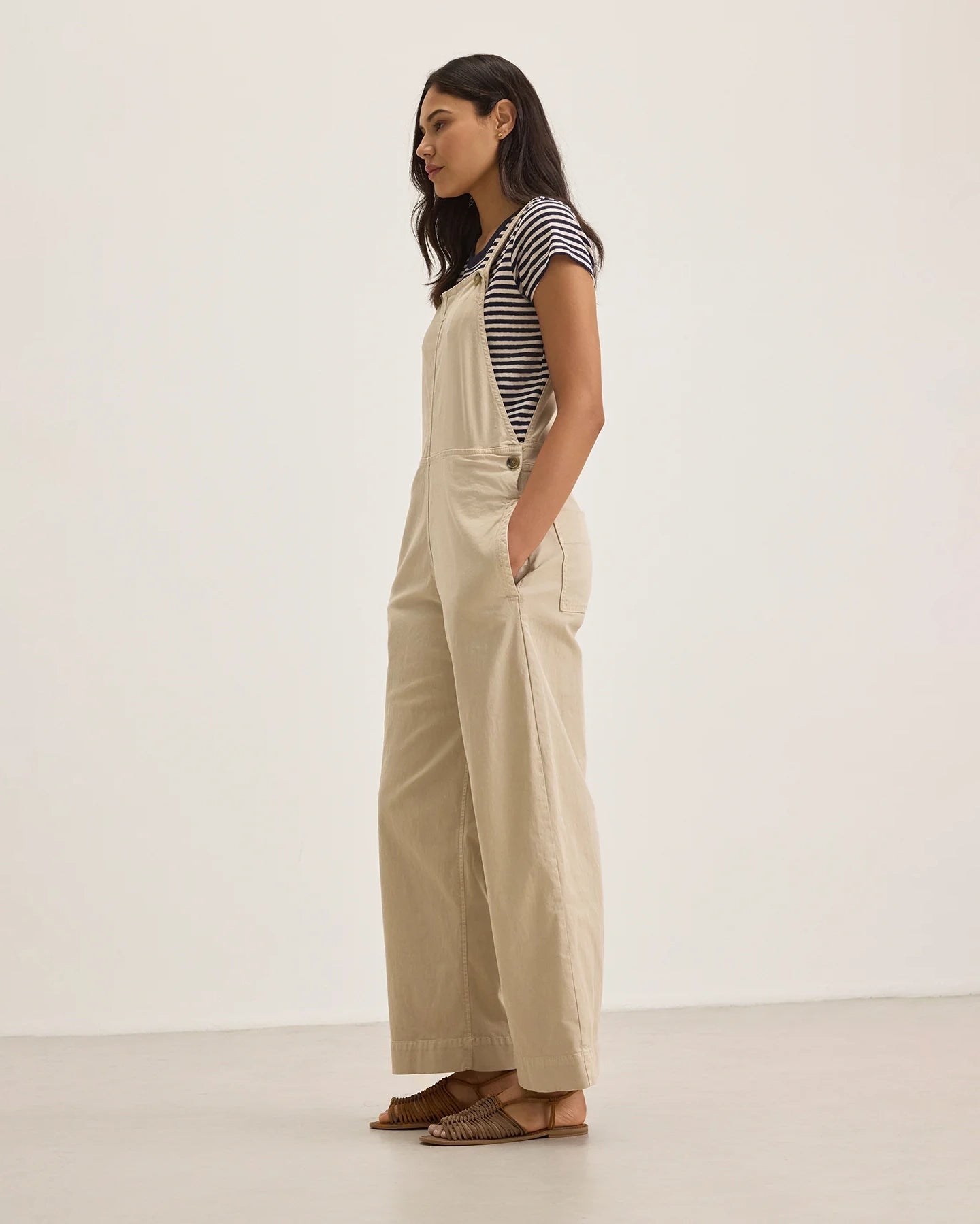 Woman wearing beige overalls with a striped shirt