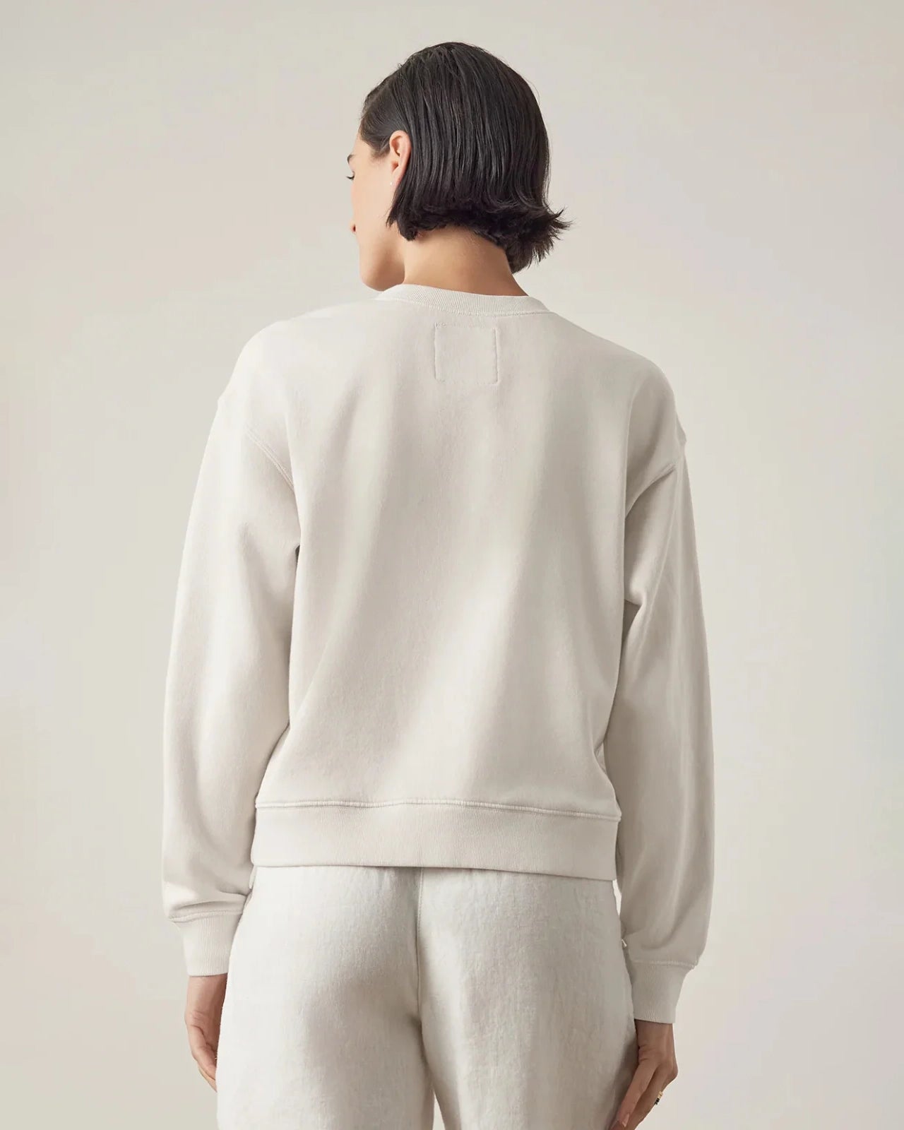 woman wearing a light gray sweatshirt from behind