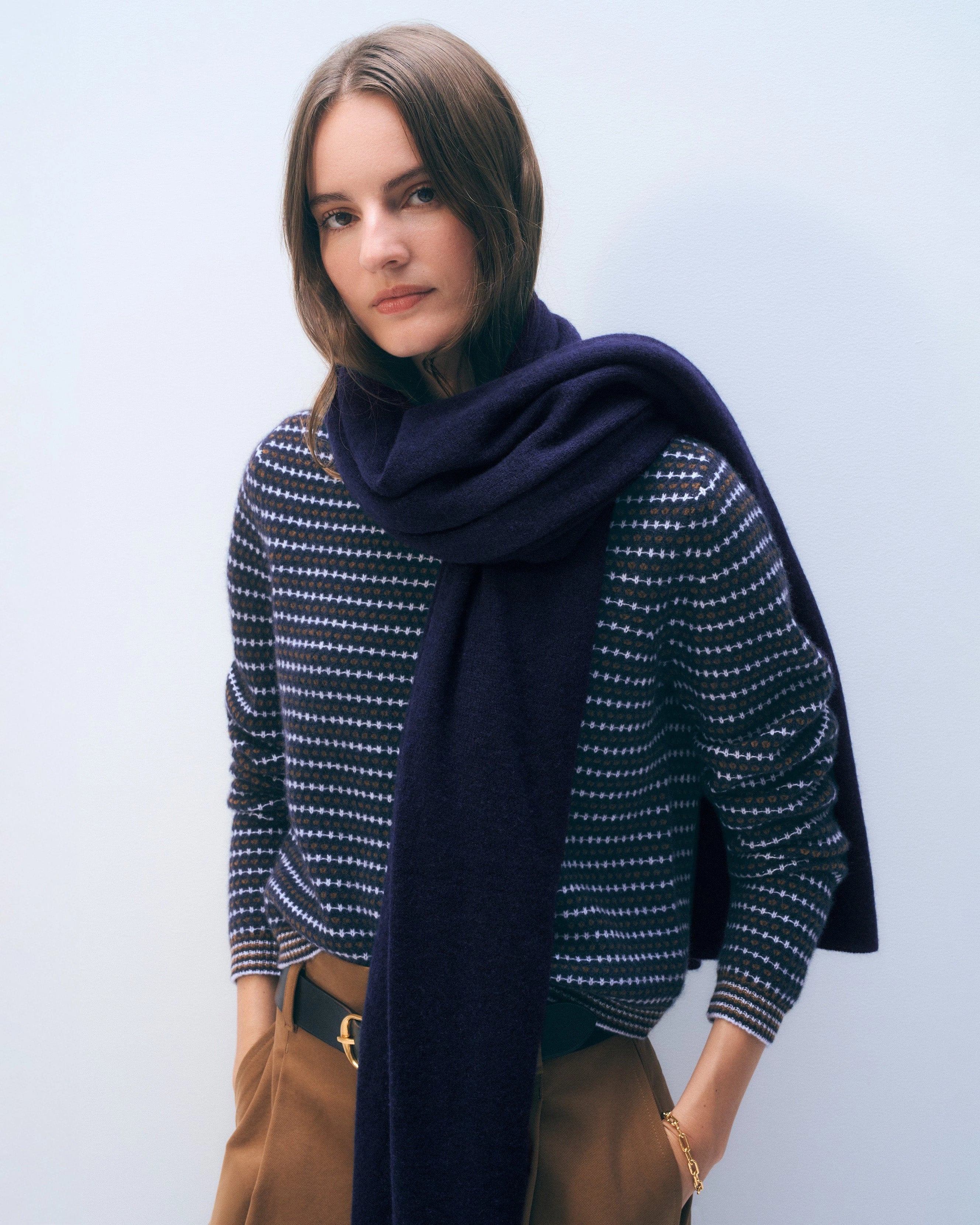 a woman wears a large cashmere travel wrap scarf in navy blue
