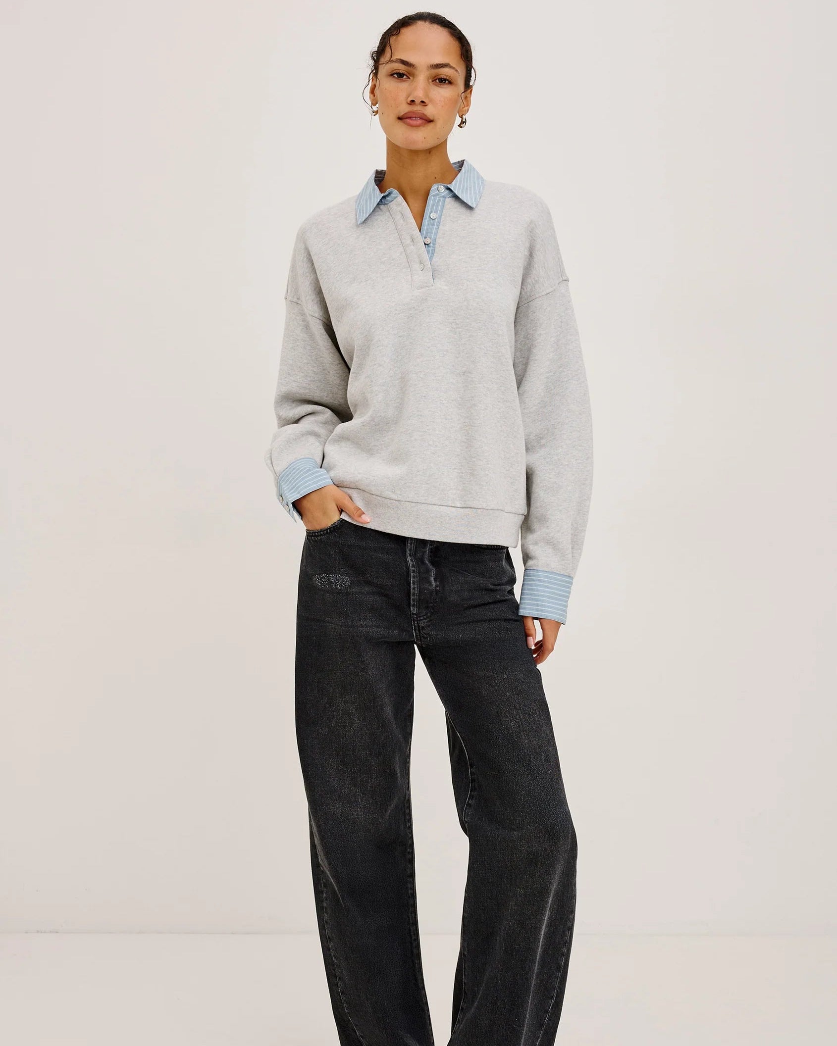 grey pullover sweatshirt with half buttons down and a blue striped collar