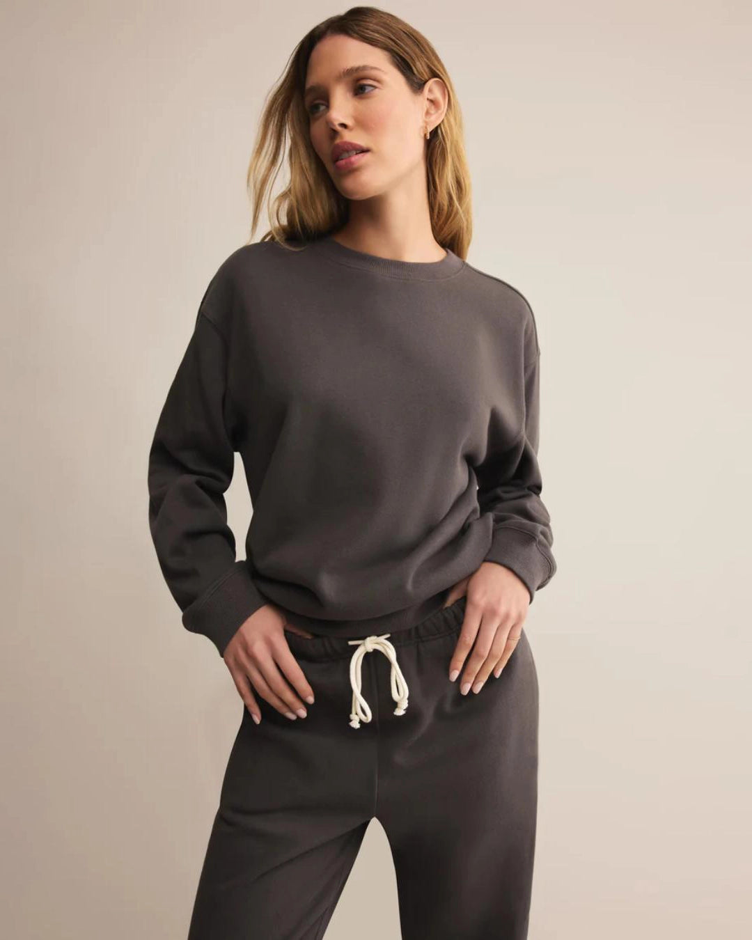 Woman wearing a dark gray cotton sweatshirt with matching sweatpants