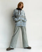 woman wearing a geometric fairisle patterned button down cardigan sweater in light. blue with green accents