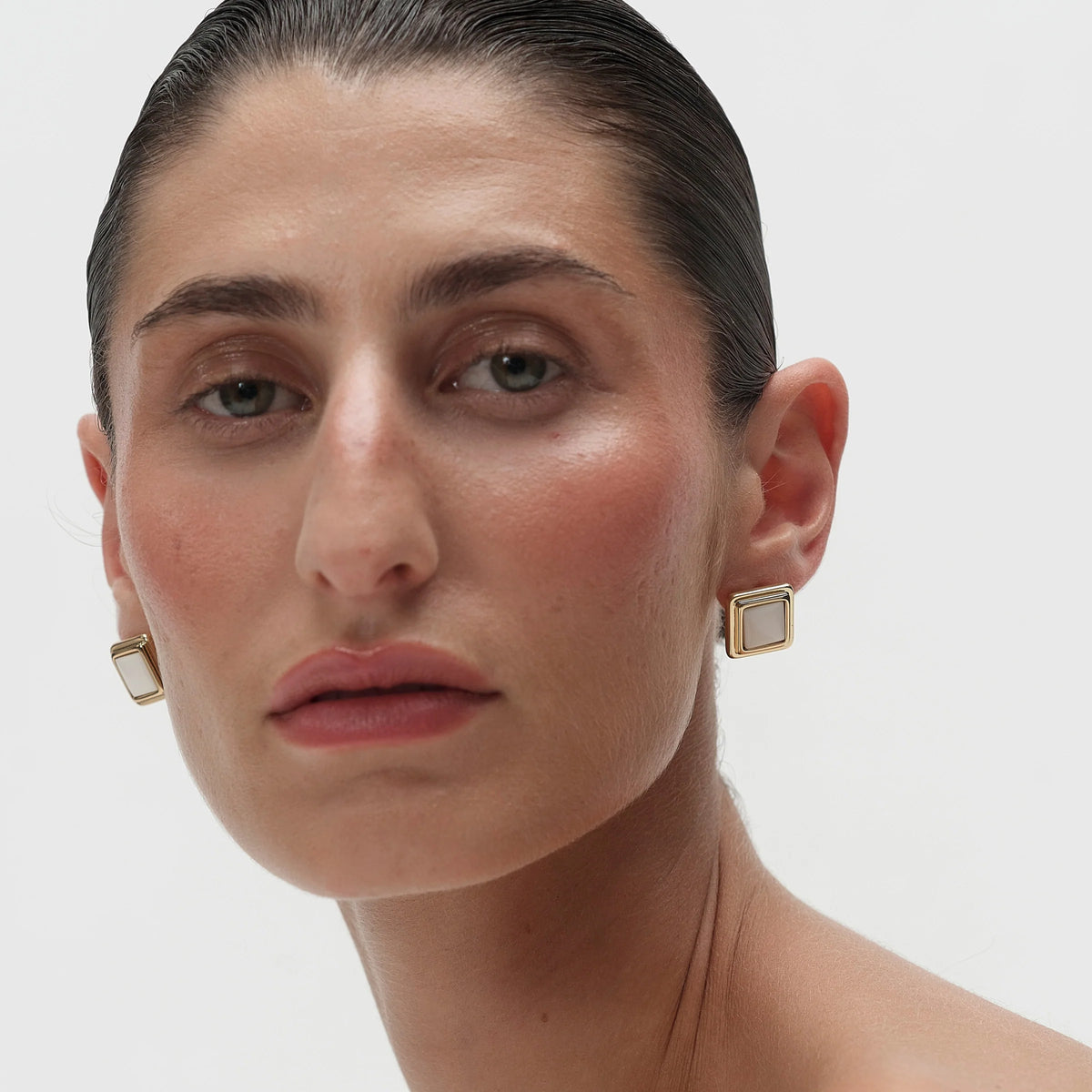 large square gold earrings with white stone in the middle