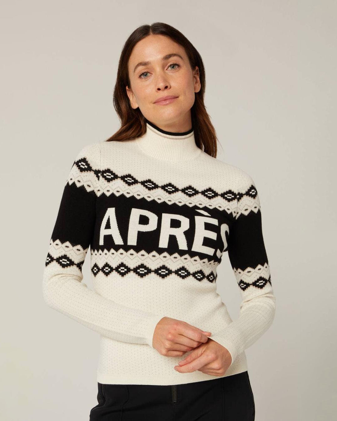 a woman wearing a fairisle black and white holiday sweater with the word 'Après' on it