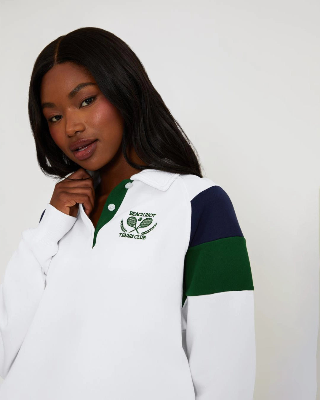 Woman wearing a white tennis top with green and navy accents