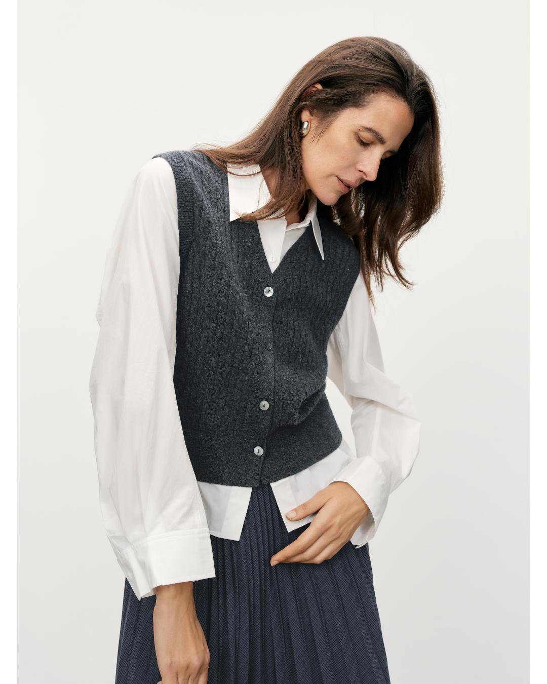 white blouse under a grey knit vest