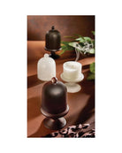 candle in a brown holder with a cloche