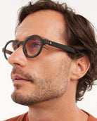 a man wears a black round framed eyeglasses for blue light by Barner