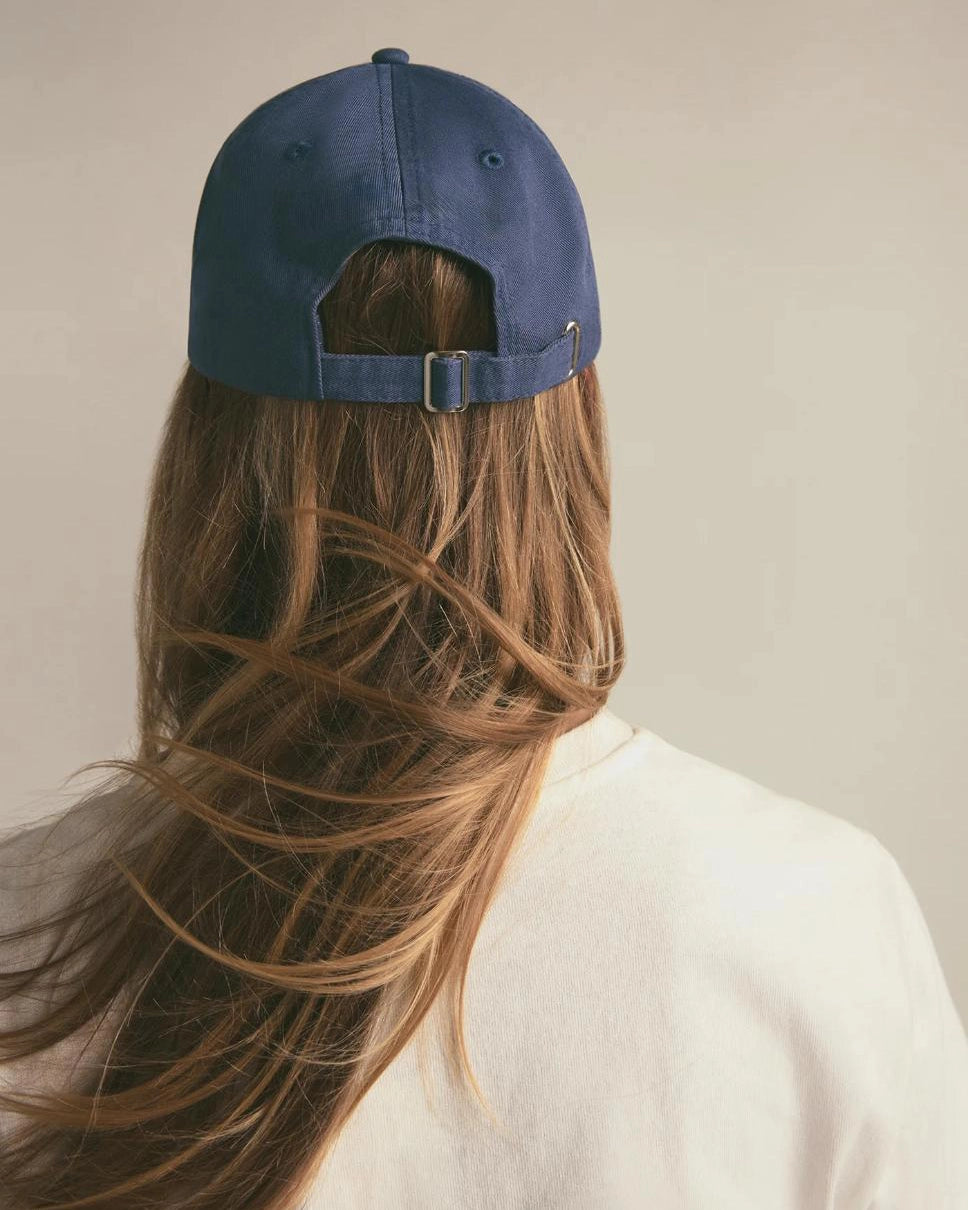 Person wearing a blue cap with long hair flowing freely.
