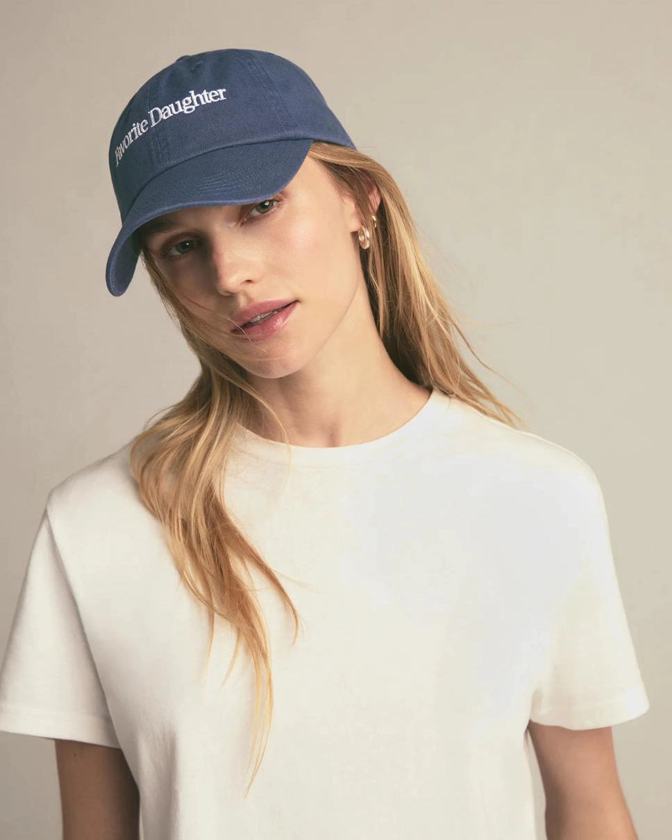 Woman wearing a navy blue baseball cap with 'Favorite Daughter' on it