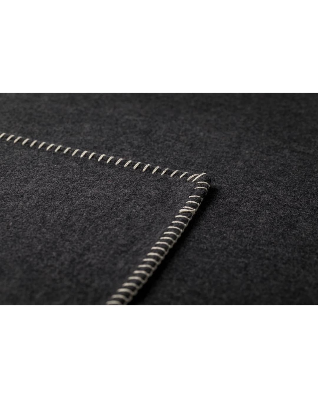 dark grey blanket with white stitching