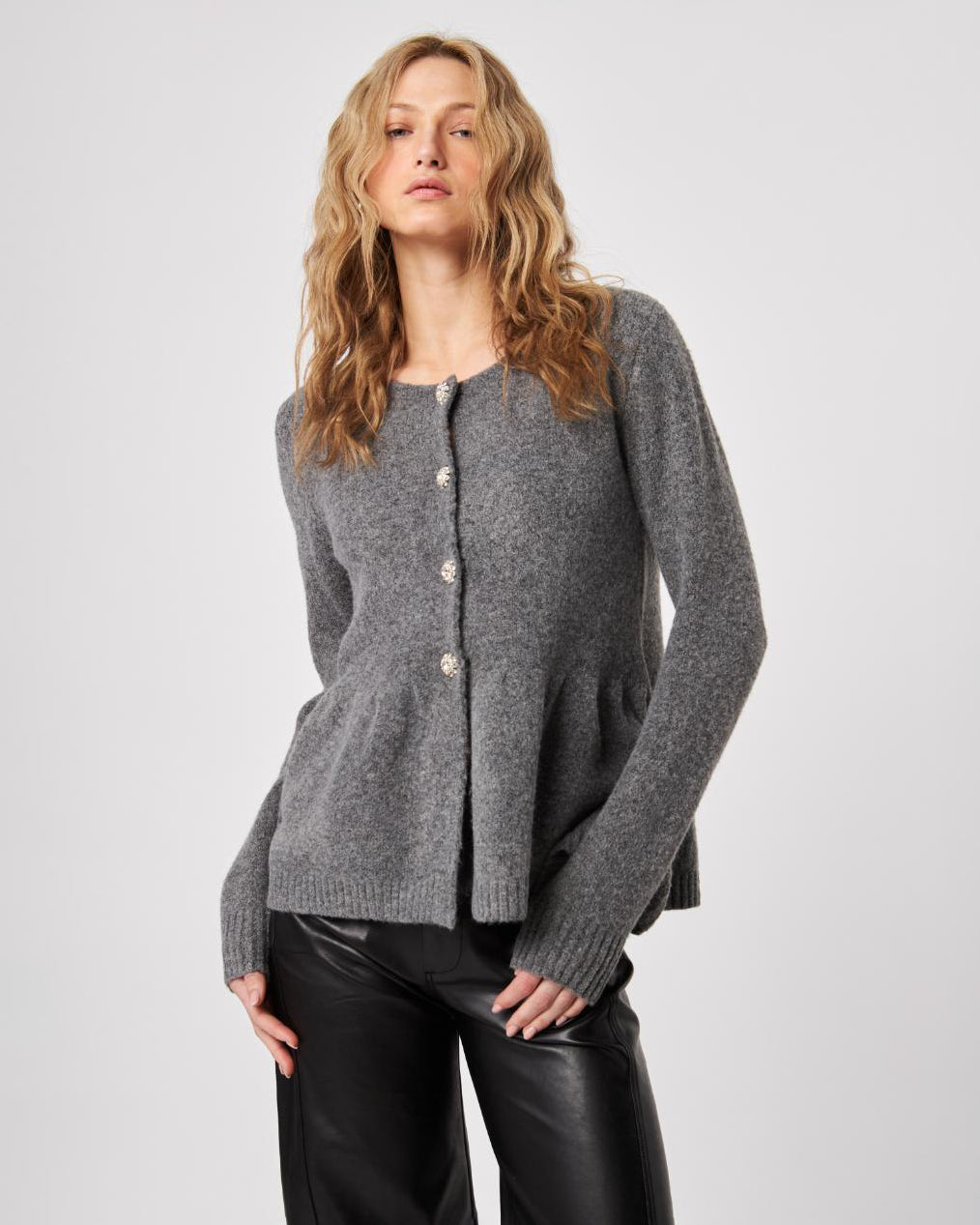 Woman wearing a gray peplum knitted button down cardigan sweater