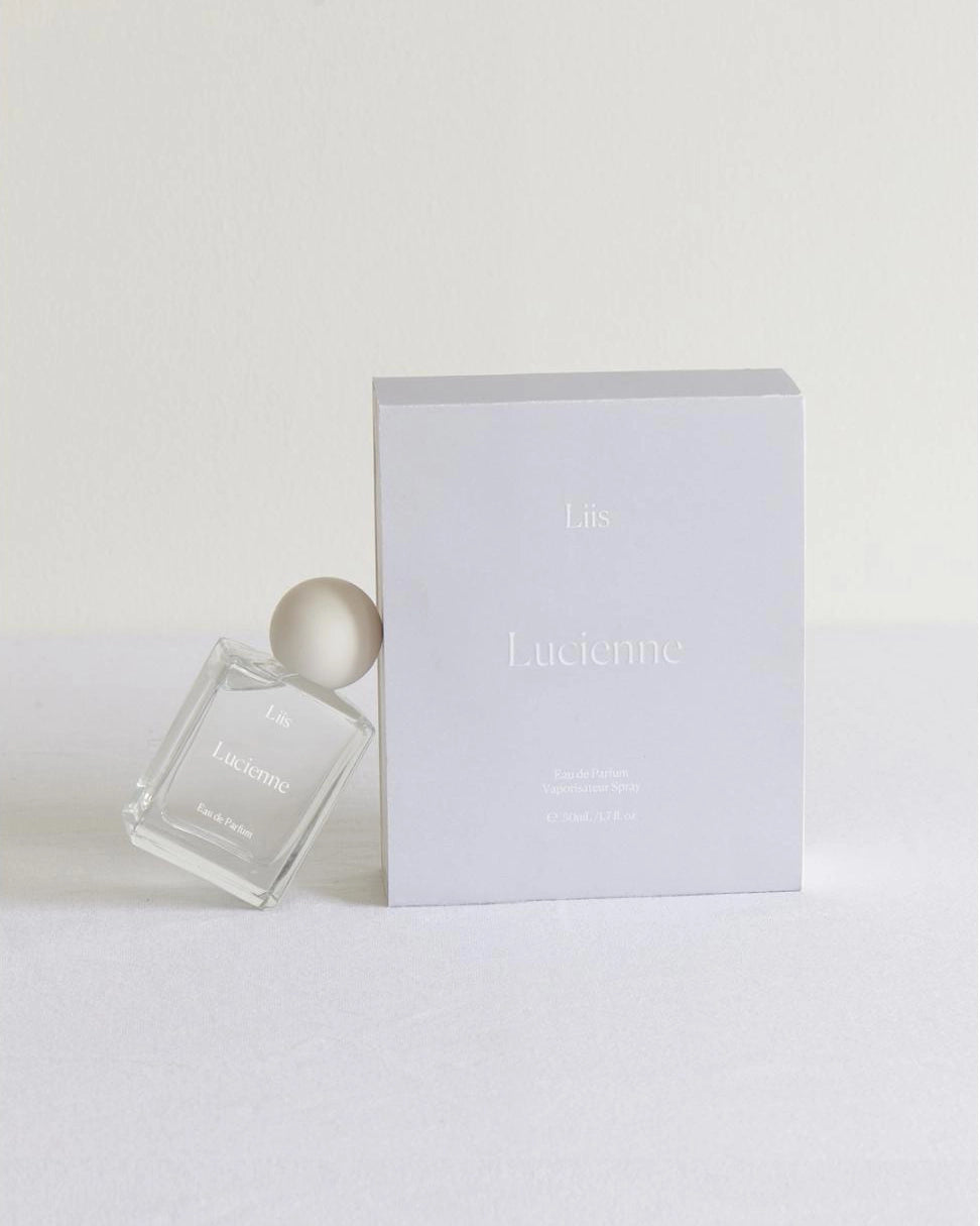 White perfume bottle with a white cap on a white background that says 'Lucienne' on it