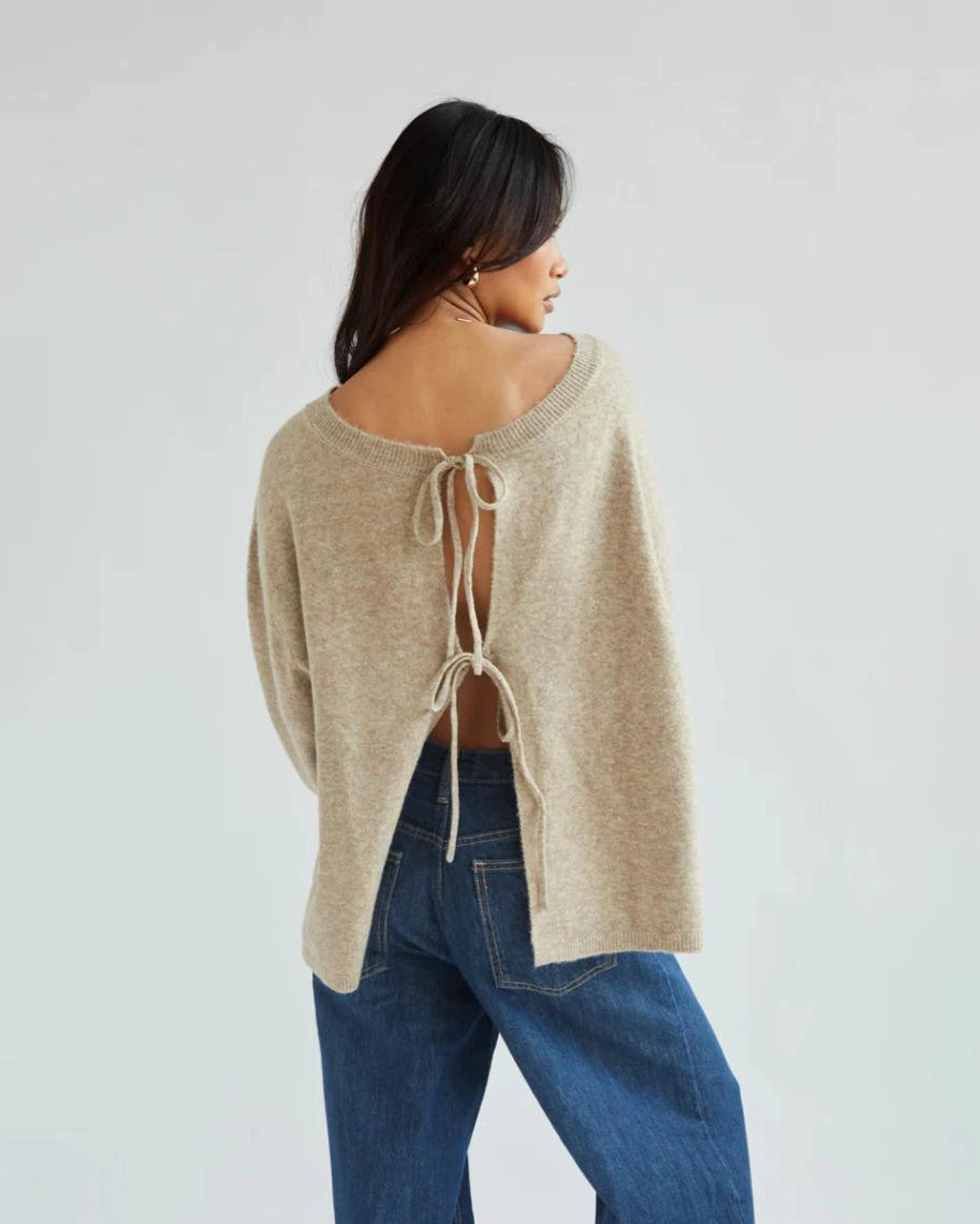 a woman wears a reversible cardigan sweater in beige with bow closures