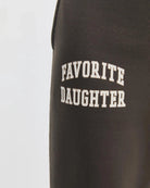 close up of brown sweatpants with 'favourite daughter' in varsity letters on them