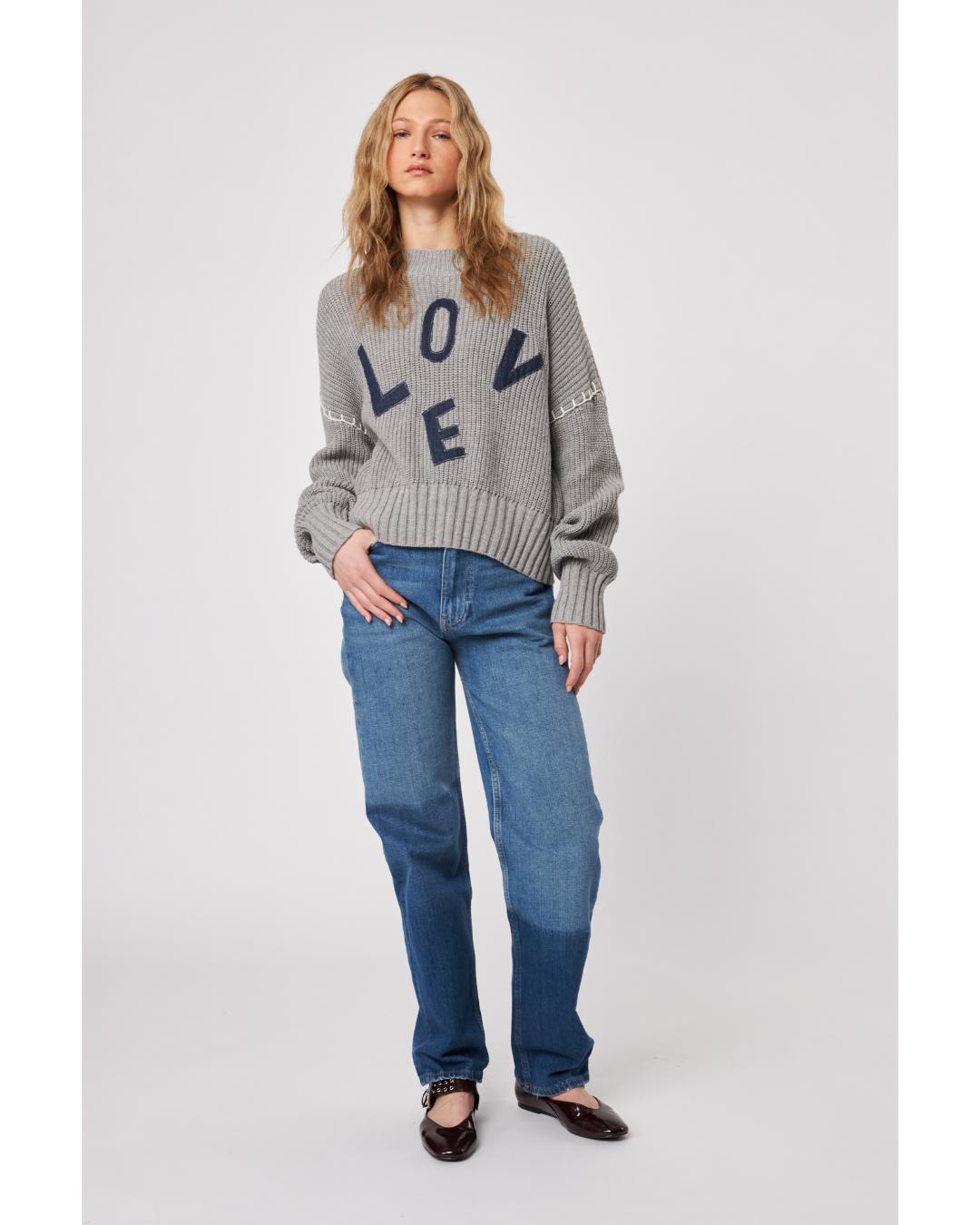Woman wearing a gray sweater with 'LOVE' printed on it