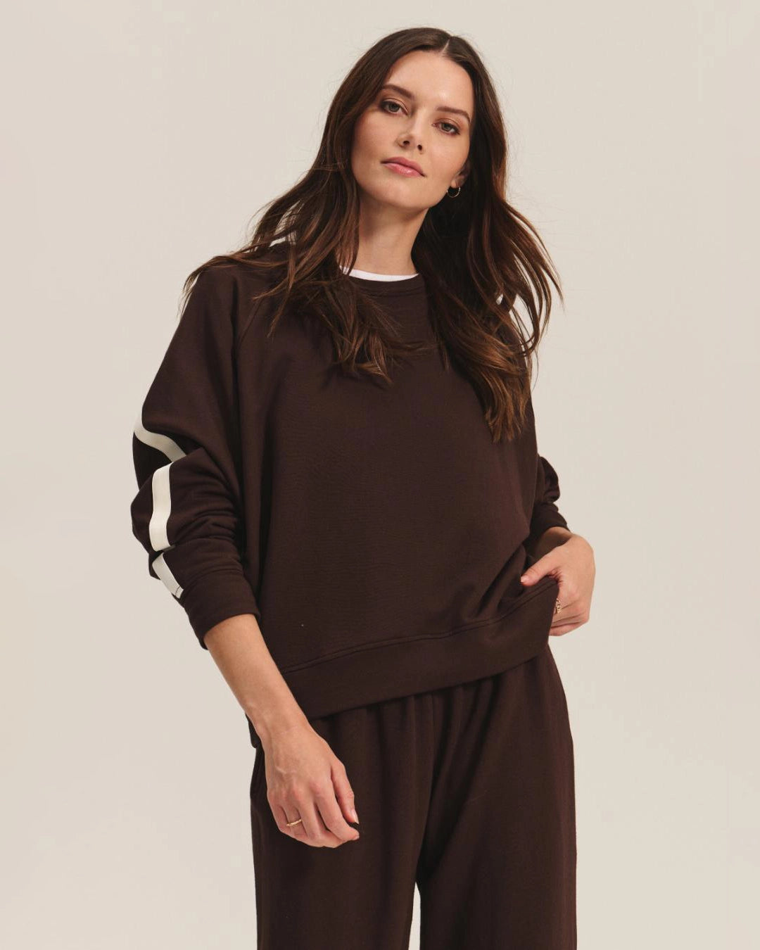 Woman wearing a brown sweatshirt with white stripes and matching pants