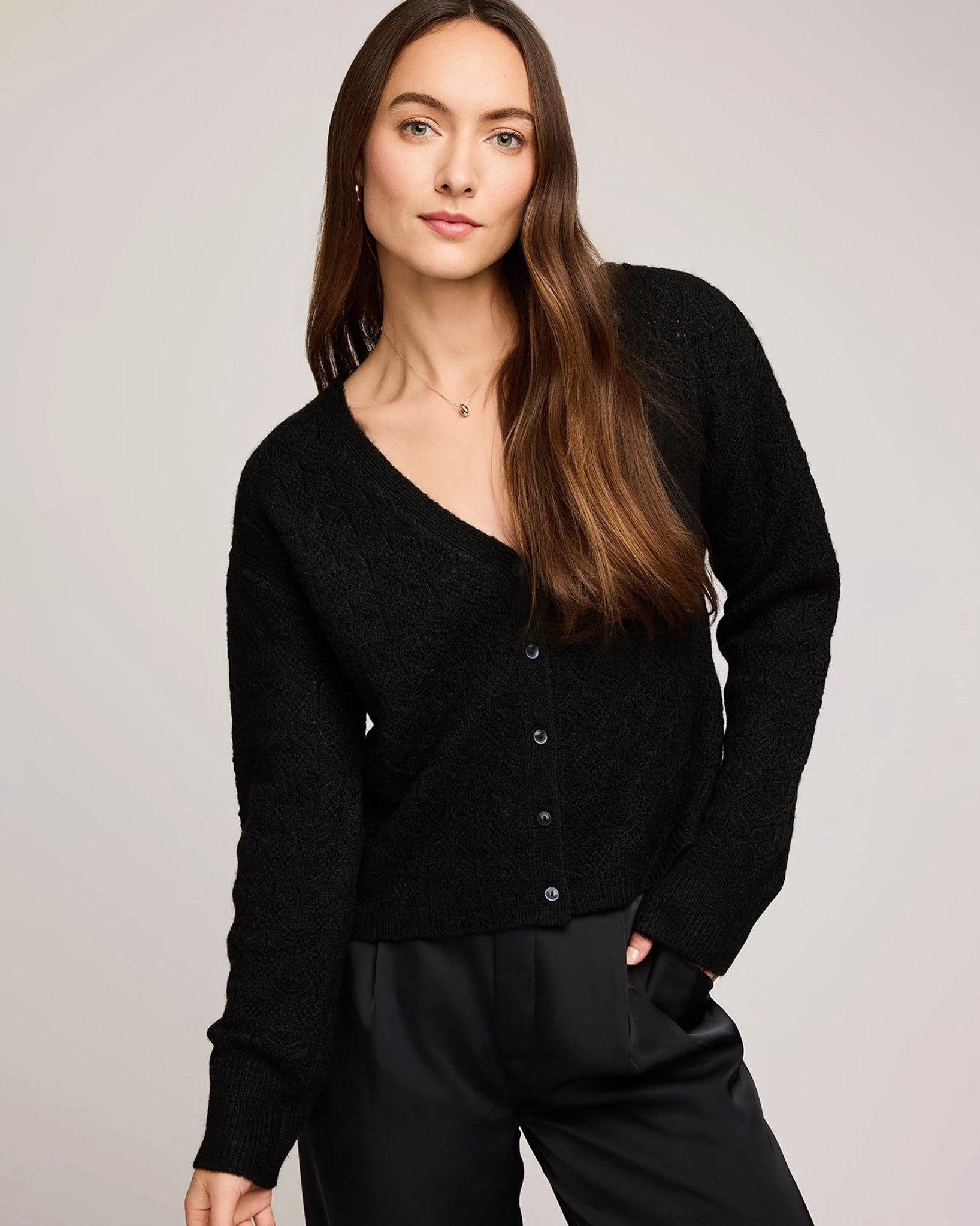 a woman wears a pointelle v neck button down cardigan in black by gentle fawn