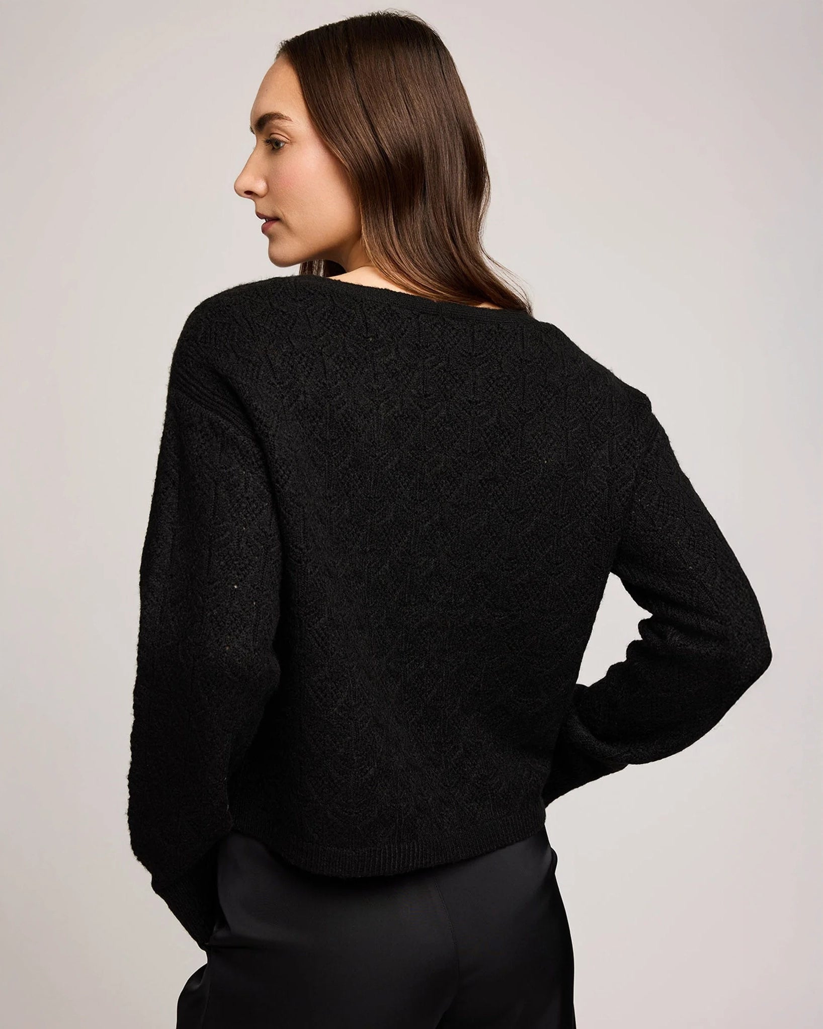 a woman wears a pointelle v neck button down cardigan in black by gentle fawn