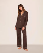 Woman wearing a chocolate brown set of modal pajamas with ivory piping by Eberjey