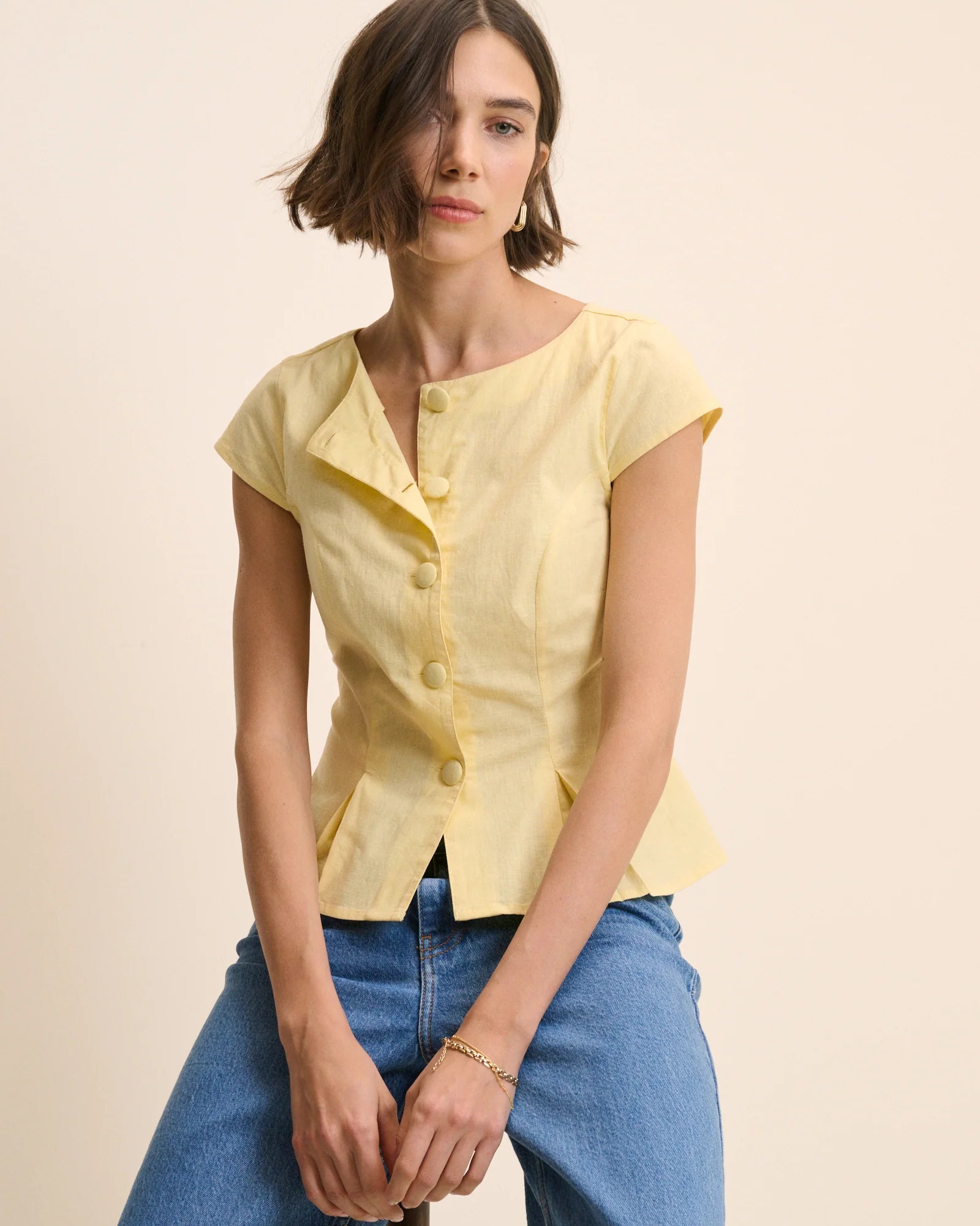 yellow top with buttons down the front and a cap sleeve