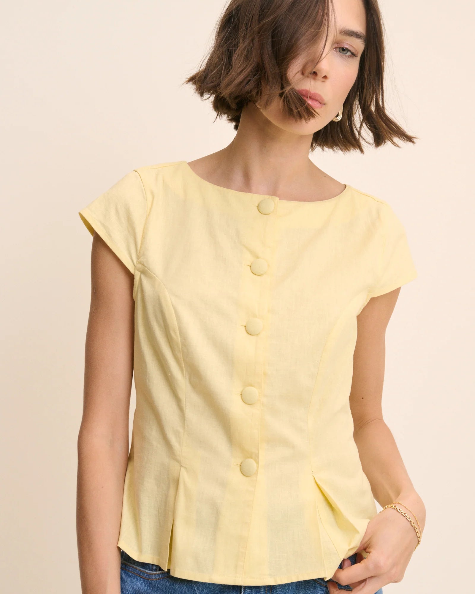 yellow top with buttons down the front and a cap sleeve