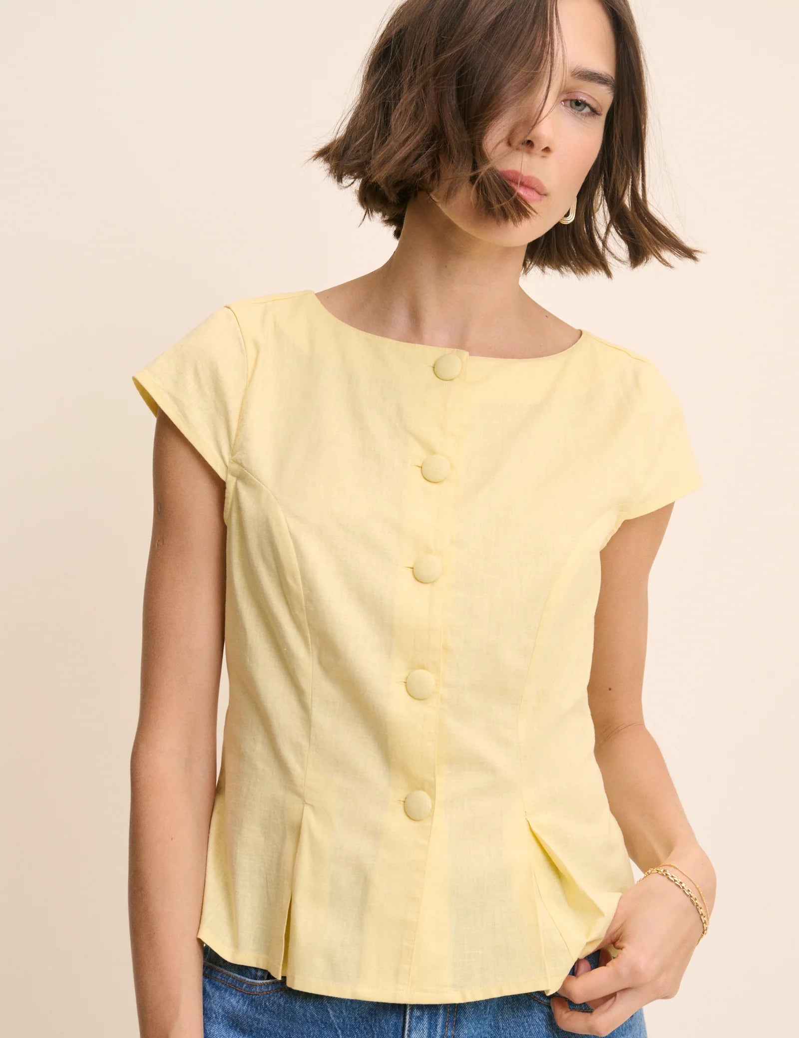 yellow top with buttons down the front and a cap sleeve