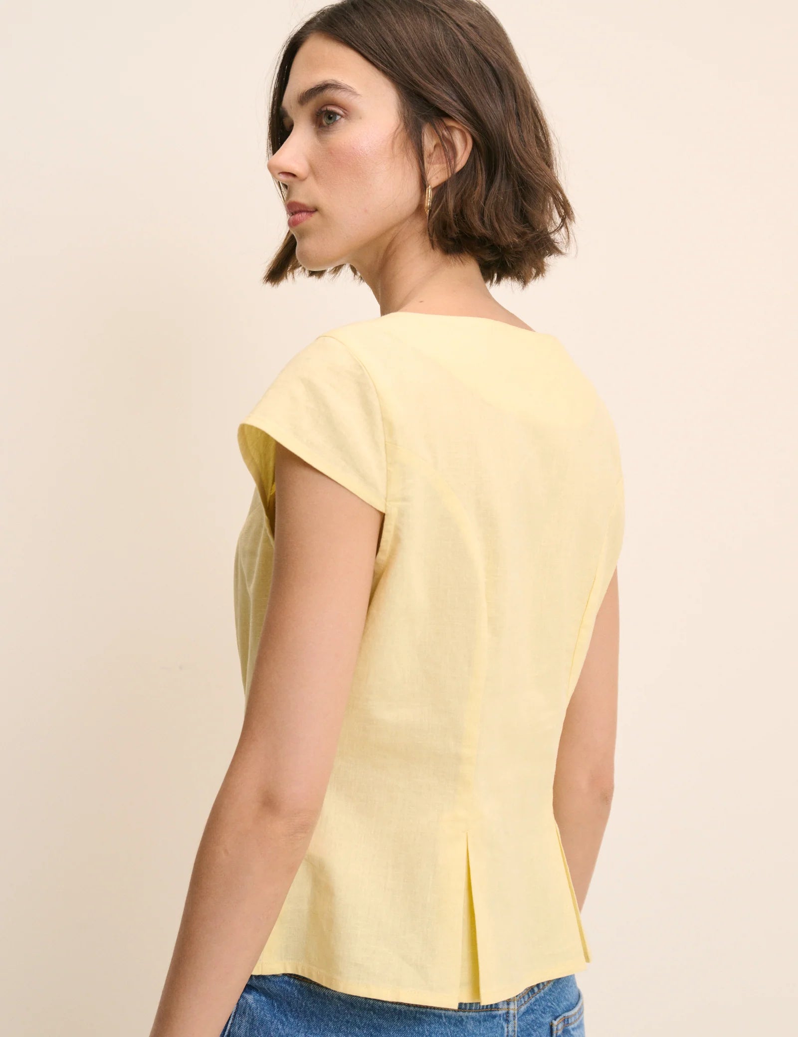 yellow top with buttons down the front and a cap sleeve