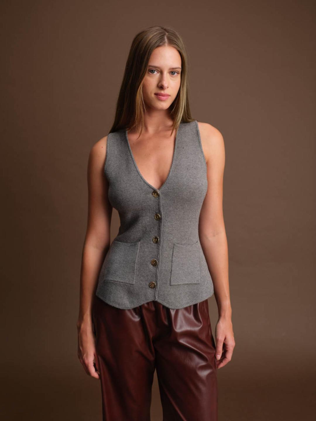 Woman wearing a grey vest with gold buttons