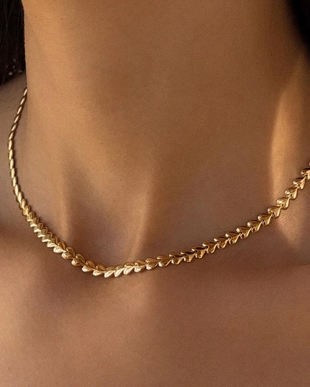 gold herring bone necklace in the shape of hearts