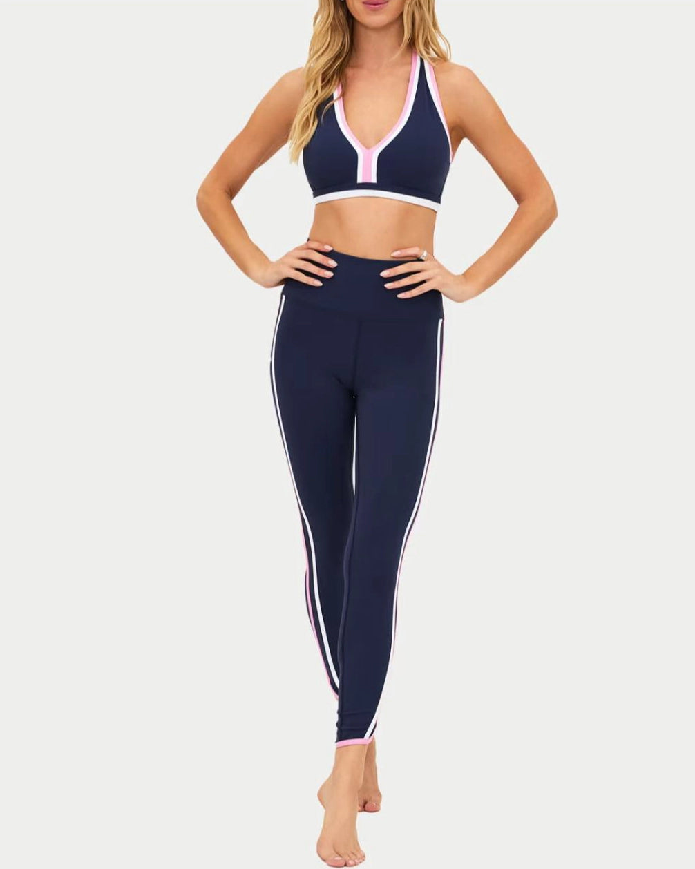 a woman wears a navy racerback sports bra with pink and white outline