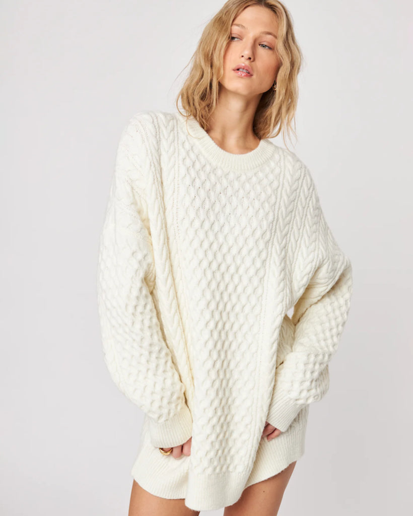 woman wearing a cable knit oversized sweater in cream