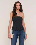 Woman wearing a black strapless peplum top