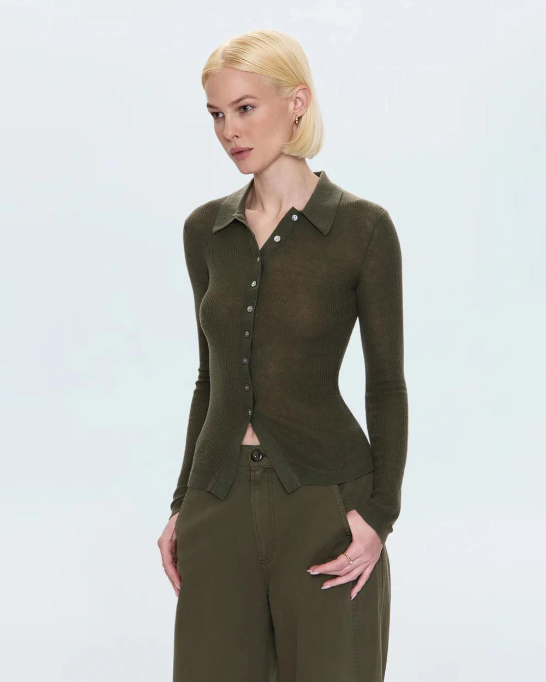 woman wearing a ribbed long sleeve top with a collar and buttons down the front in green