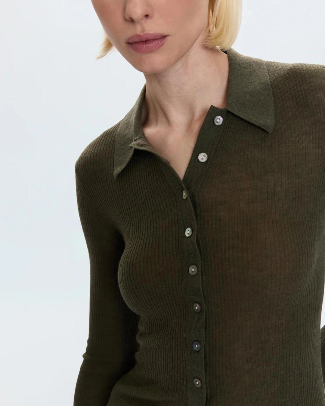 woman wearing a ribbed long sleeve top with a collar and buttons down the front in green