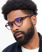 a man wears a pair of round framed tortoiseshell eyeglasses for blue light by Barner