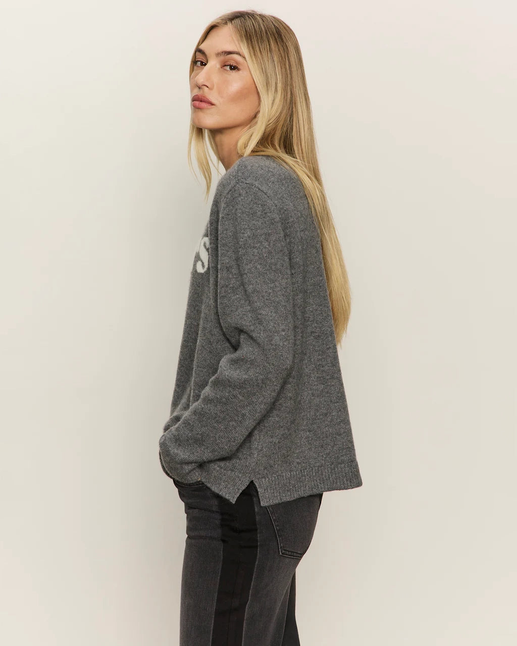 Woman wearing a gray cashmere sweater with 'cheers' text on it