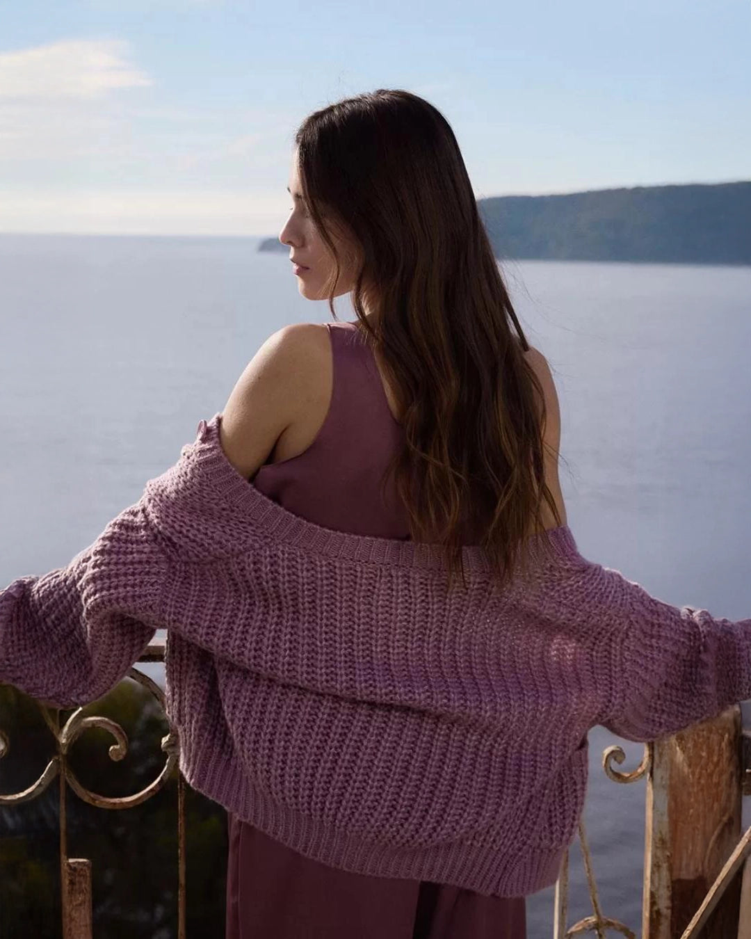 woman wearing a loose knit cardigan with large buttons and bubble sleeves in mauve purple