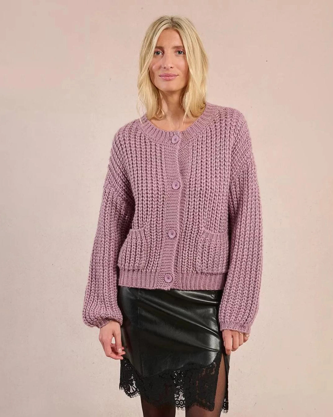 woman wearing a loose knit cardigan with large buttons and bubble sleeves in mauve purple