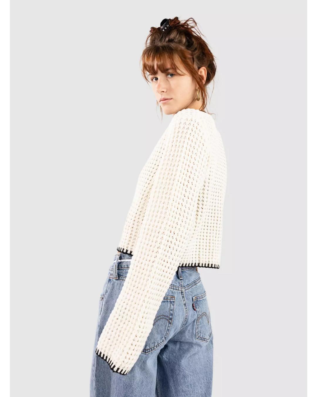 cream knit cardigan that ties in the middle with black trim on the bottom and sleeves