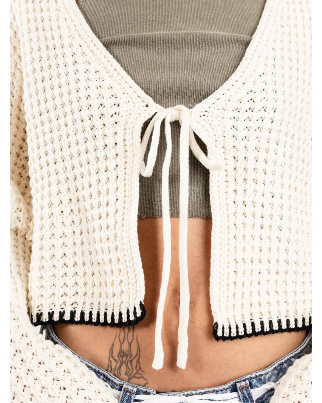 cream knit cardigan that ties in the middle with black trim on the bottom and sleeves