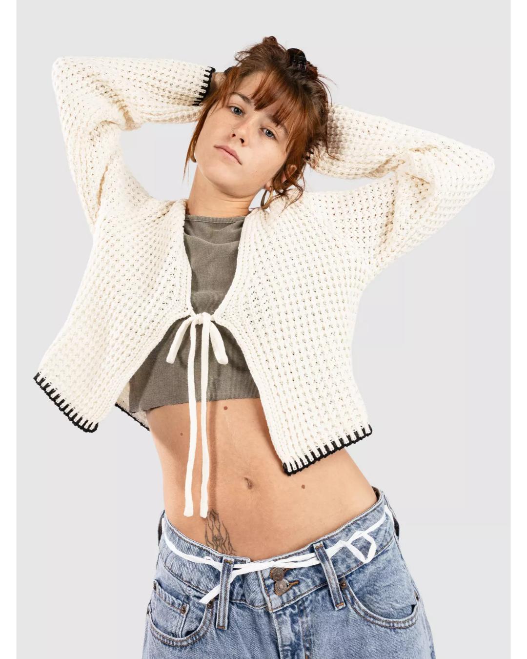 cream knit cardigan that ties in the middle with black trim on the bottom and sleeves