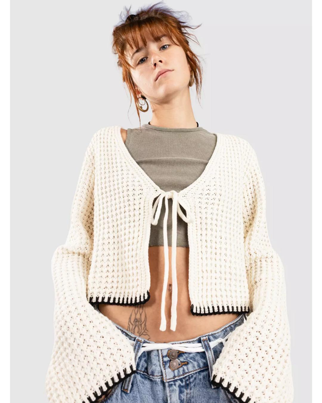 cream knit cardigan that ties in the middle with black trim on the bottom and sleeves