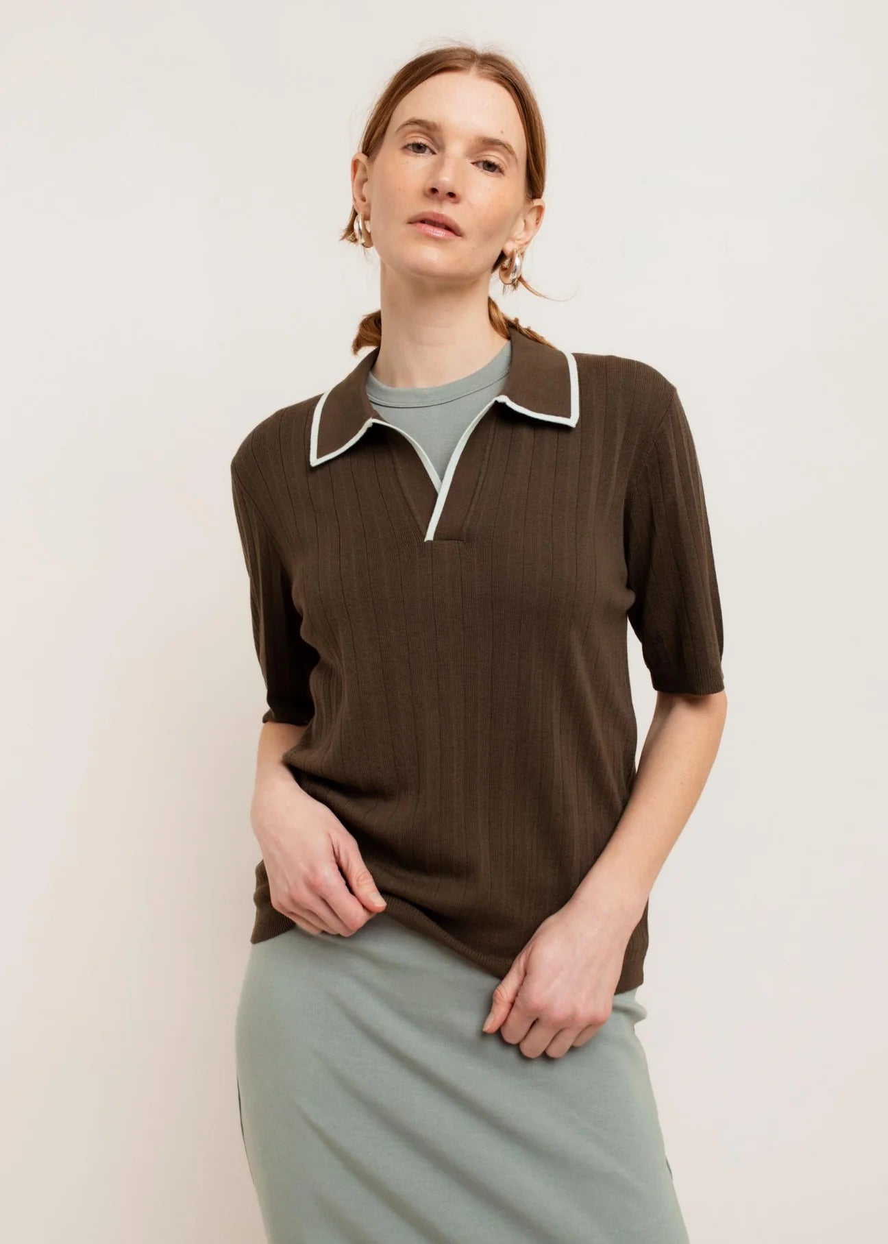 polo shirt in dark green with a white outline on the collar