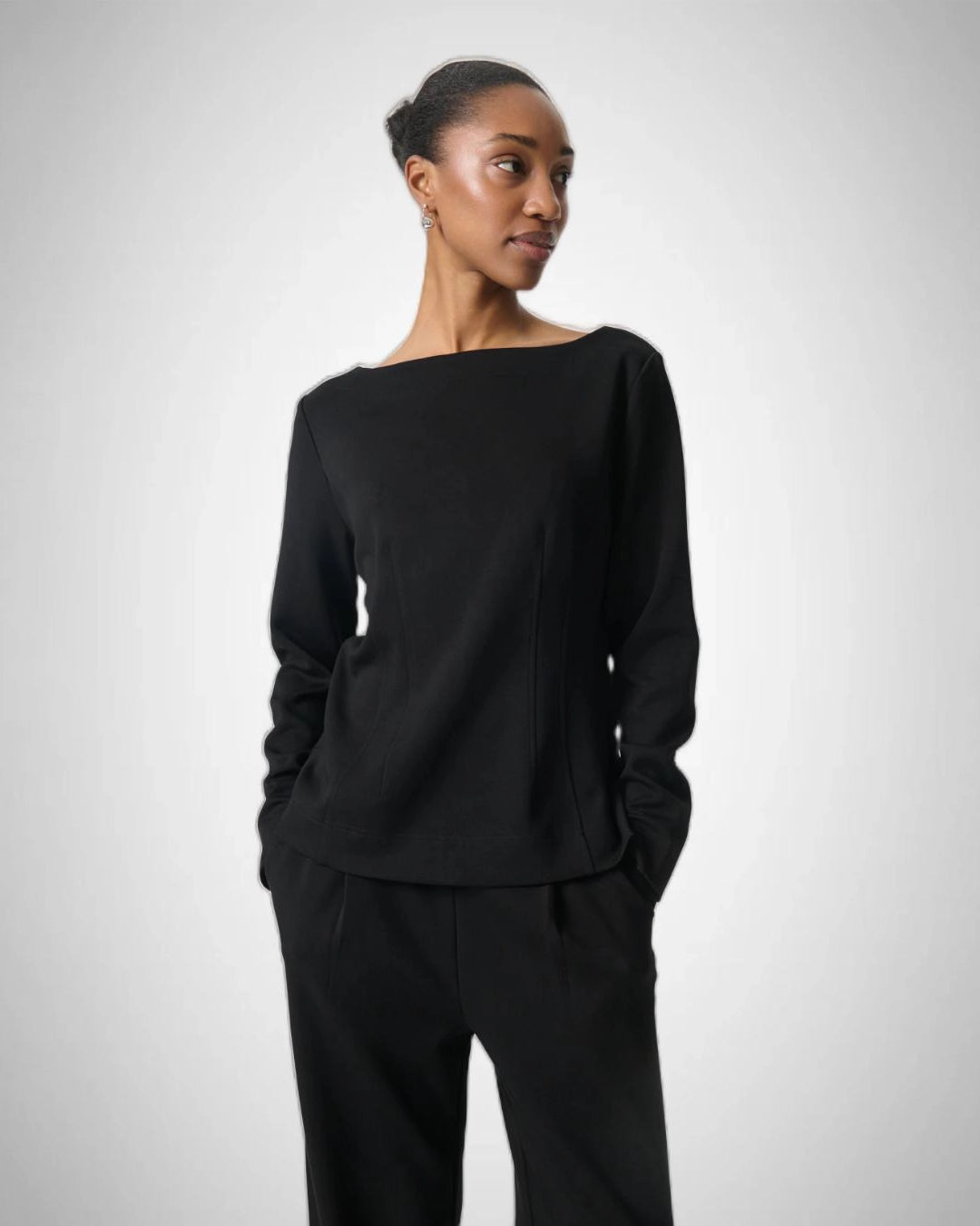 Woman wearing a black long-sleeve top with a boat neckline